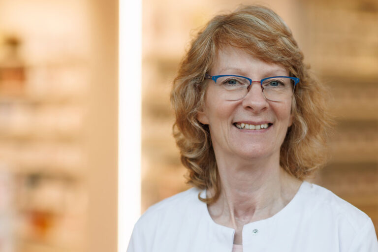 Portraitfoto Ursula Steinbrecher, Drogistin. Die Apotheken-Mitarbeiterin lacht in die Kamera.